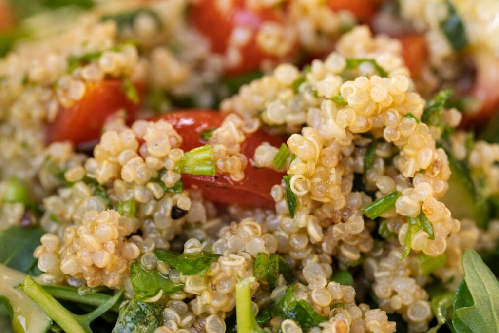 Close-up of fluffy cooked quinoa mixed with diced tomato and fresh herbs, a naturally gluten-free grain