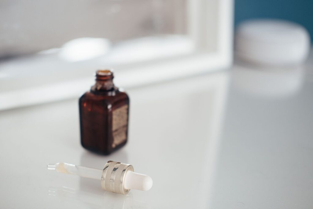 Small amber glass bottle with a dropper lying beside it on a white surface, like a bottle of vanilla extract.