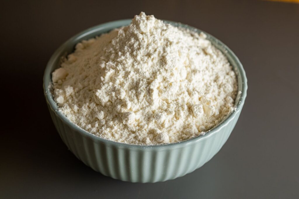 Heaped bowl of fine white wheat starch powder in a pale green ribbed bowl, illustrating whether wheat starch is gluten free